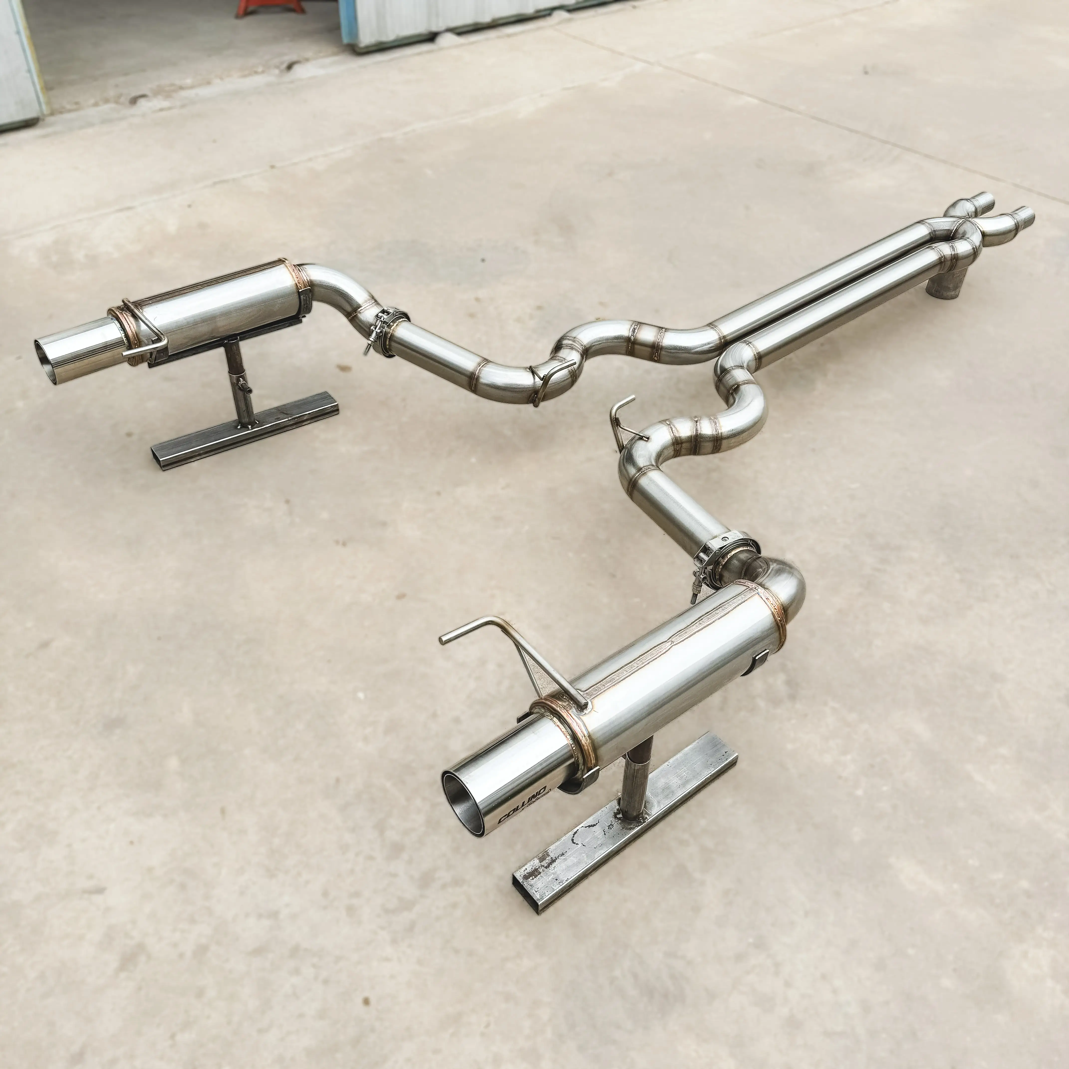 Collino Mustang exhaust system, made of stainless steel with a polished finish. The system features two primary tubes that merge smoothly into a single outlet, designed to optimize exhaust flow and improve performance. The polished finish gives the system a sleek and professional appearance, suitable for high-performance racing applications.