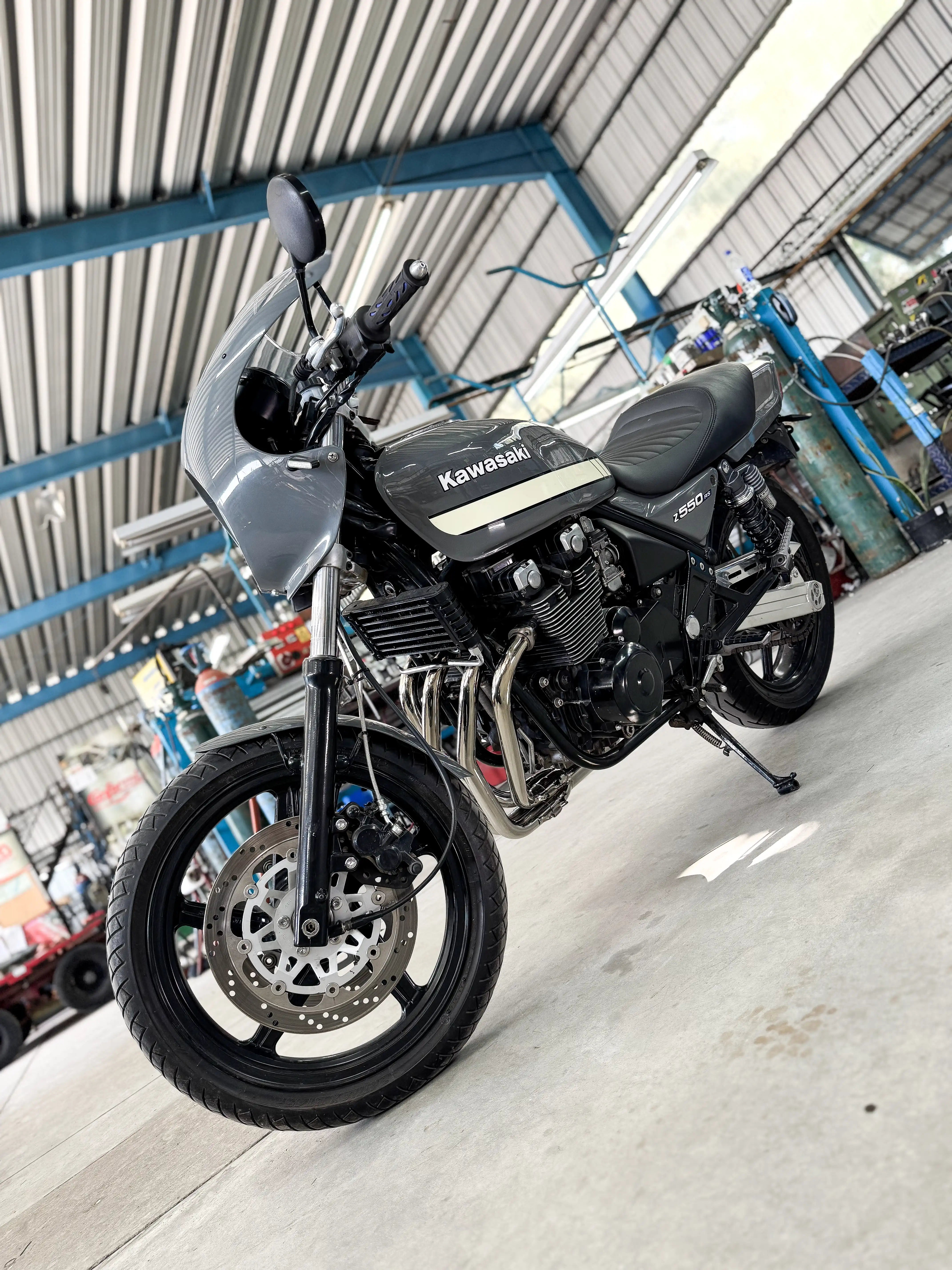 Kawasaki Z550 with a full race header installed, shown in the engine bay. The header is made of stainless steel and features smooth bends and a polished finish.